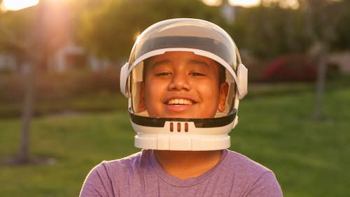 Boy Smiling While Wearing Astronaut Helmet 