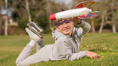 Free A joyful boy playing with a toy rocket in a sunny park, embracing imagination. Stock Photo