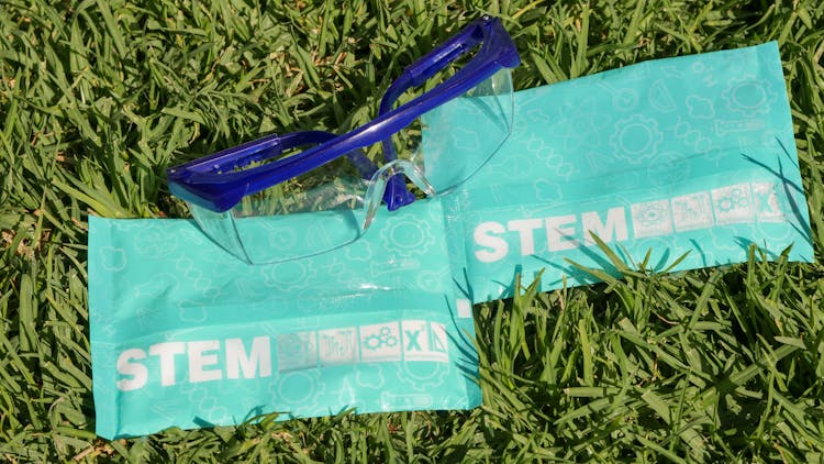 Protective Goggles And Stem Packaging On Green Grass