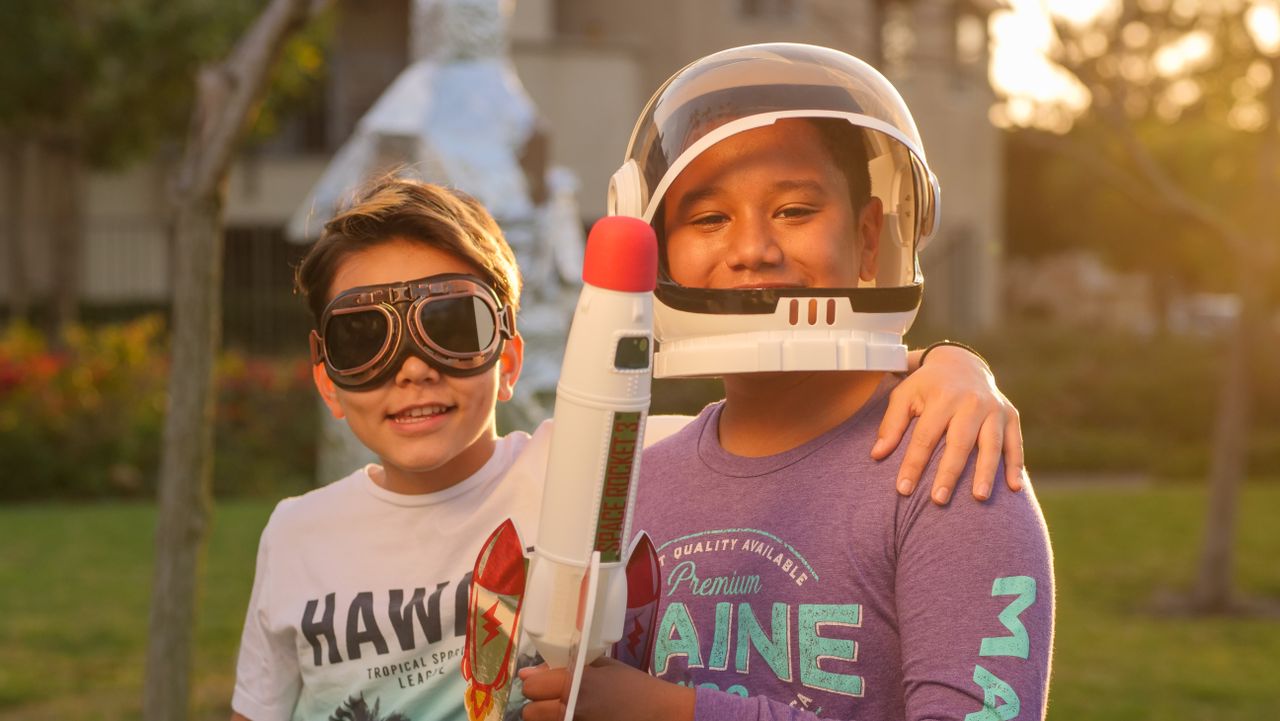 two boys enjoying imaginative play as astronauts outdoors at sunset cr