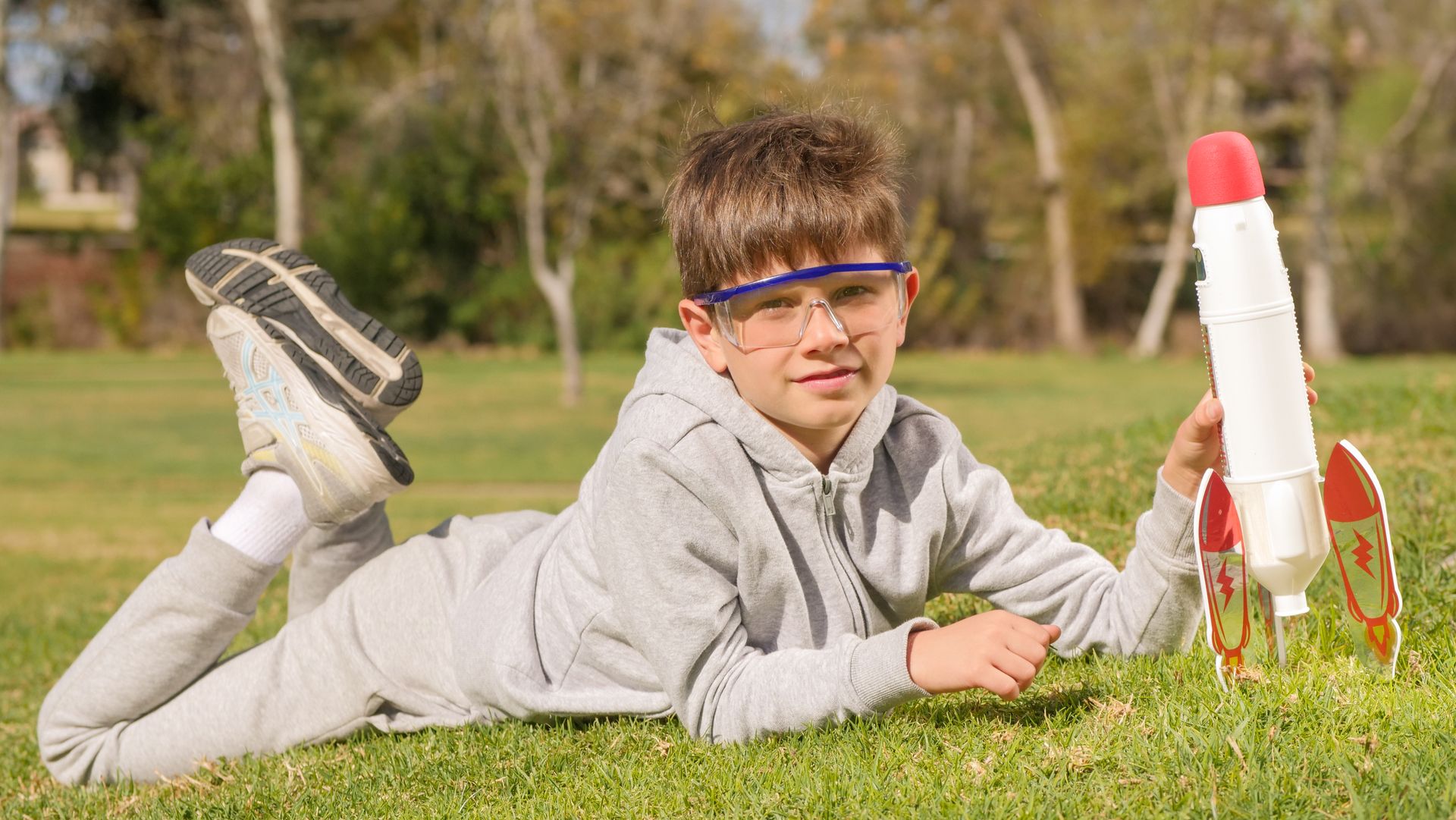A Boy Wearing Protective Goggles Holding a Toy Rocket