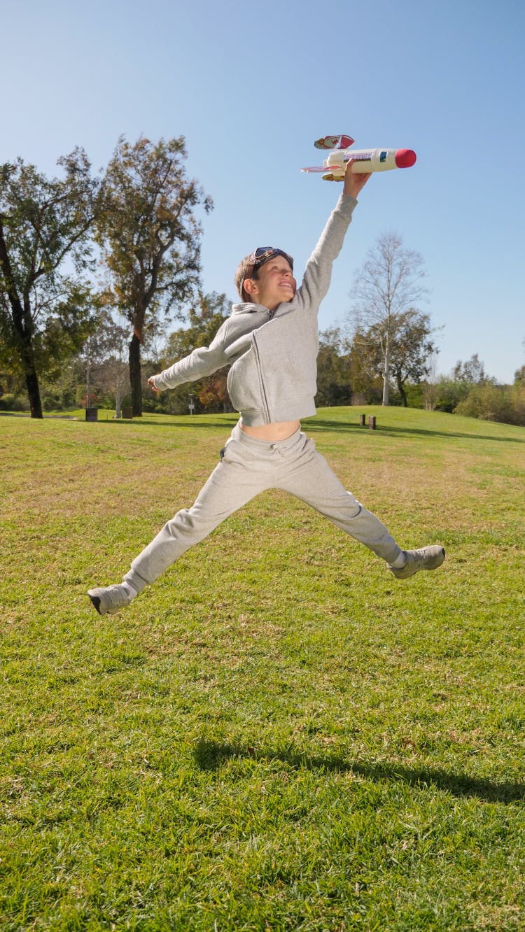 A Boy Holding A Toy Spaceship Jumping On Air