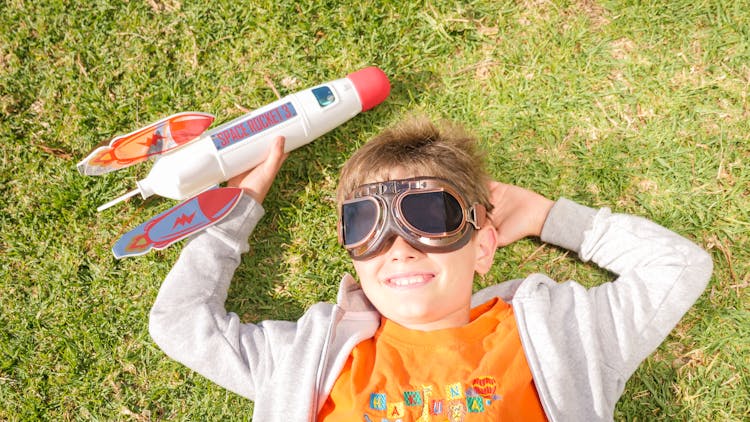 Boy Lying On Grass With His Rocket Toy