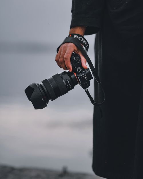 Free Close-up of a person holding a camera with blurred background outdoors. Stock Photo