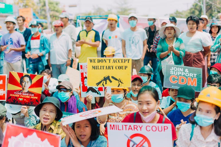 People Wearing Hats And Face Masks Holding Placards