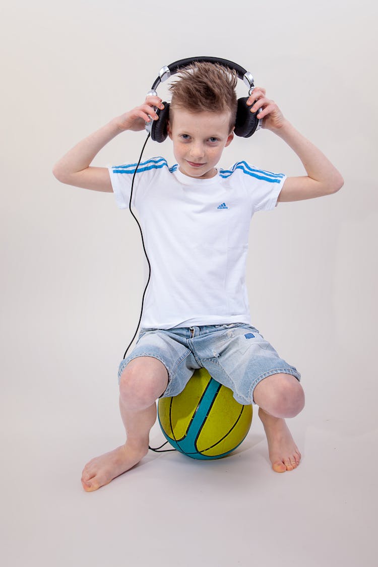 Boy Sitting On A Ball While Wearing Headset 