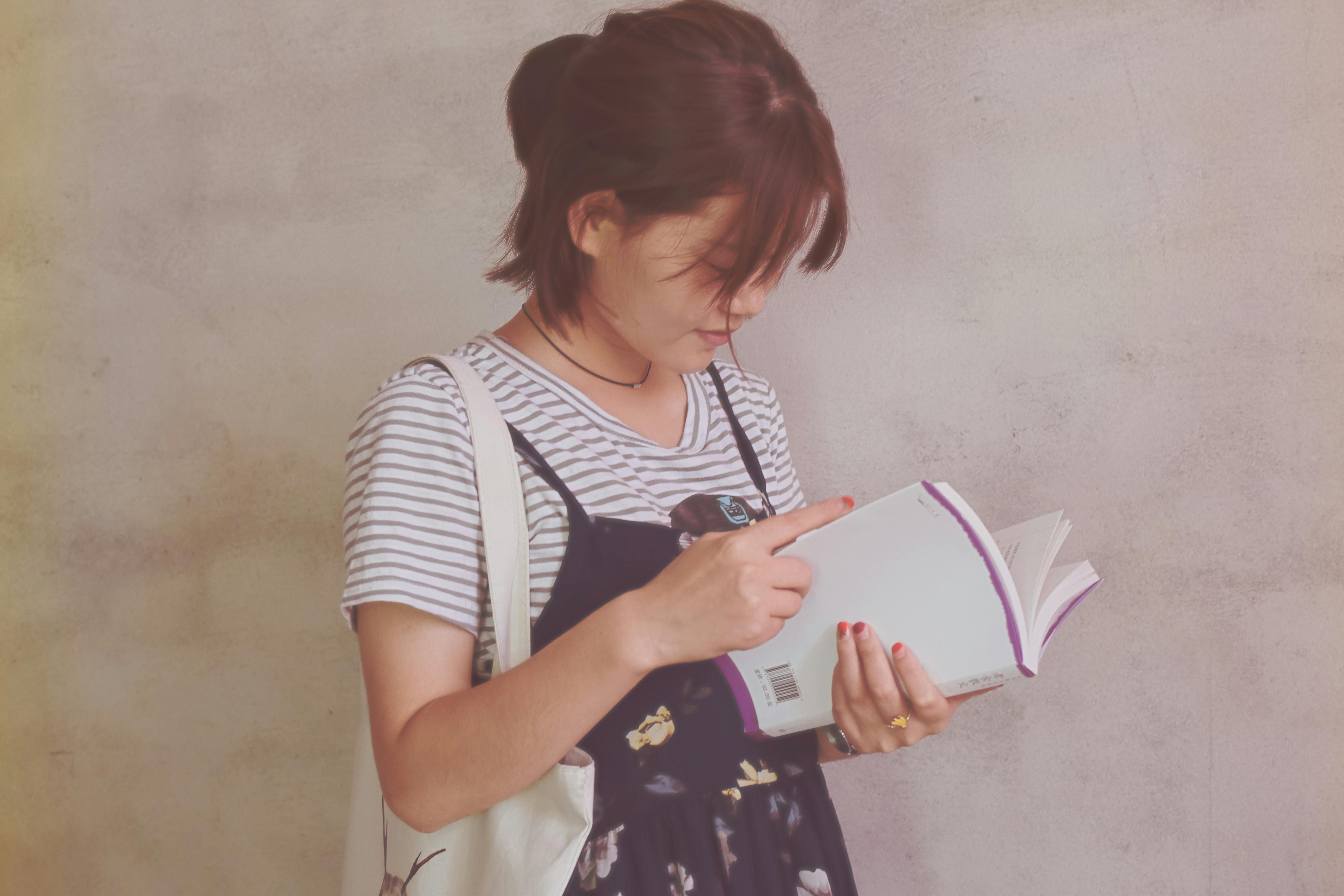 Girl holding a white book. | Photo: Pexels