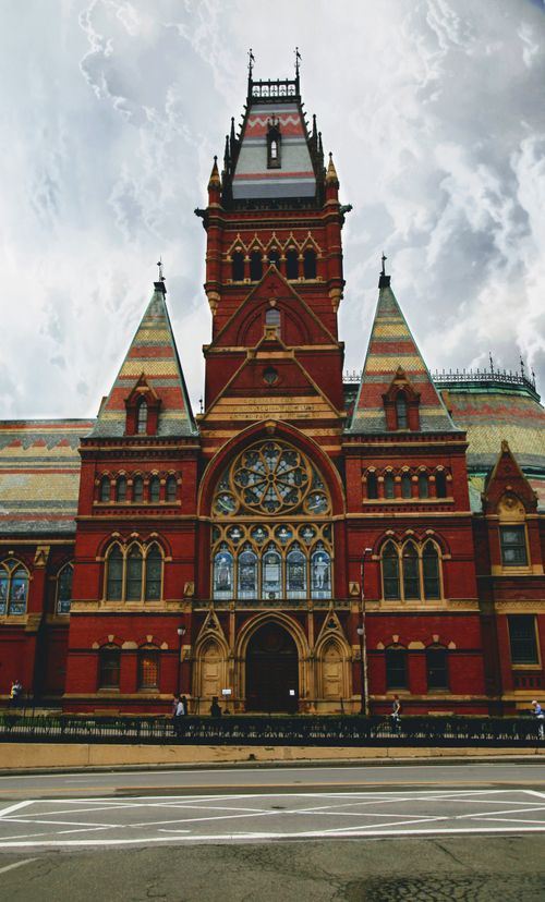 Free Memorial Hall in Harvard University showcasing Victorian Gothic architecture against a cloudy sky. Stock Photo