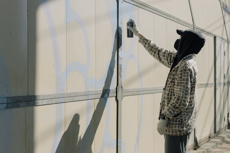 A Man Spray Painting A Wall