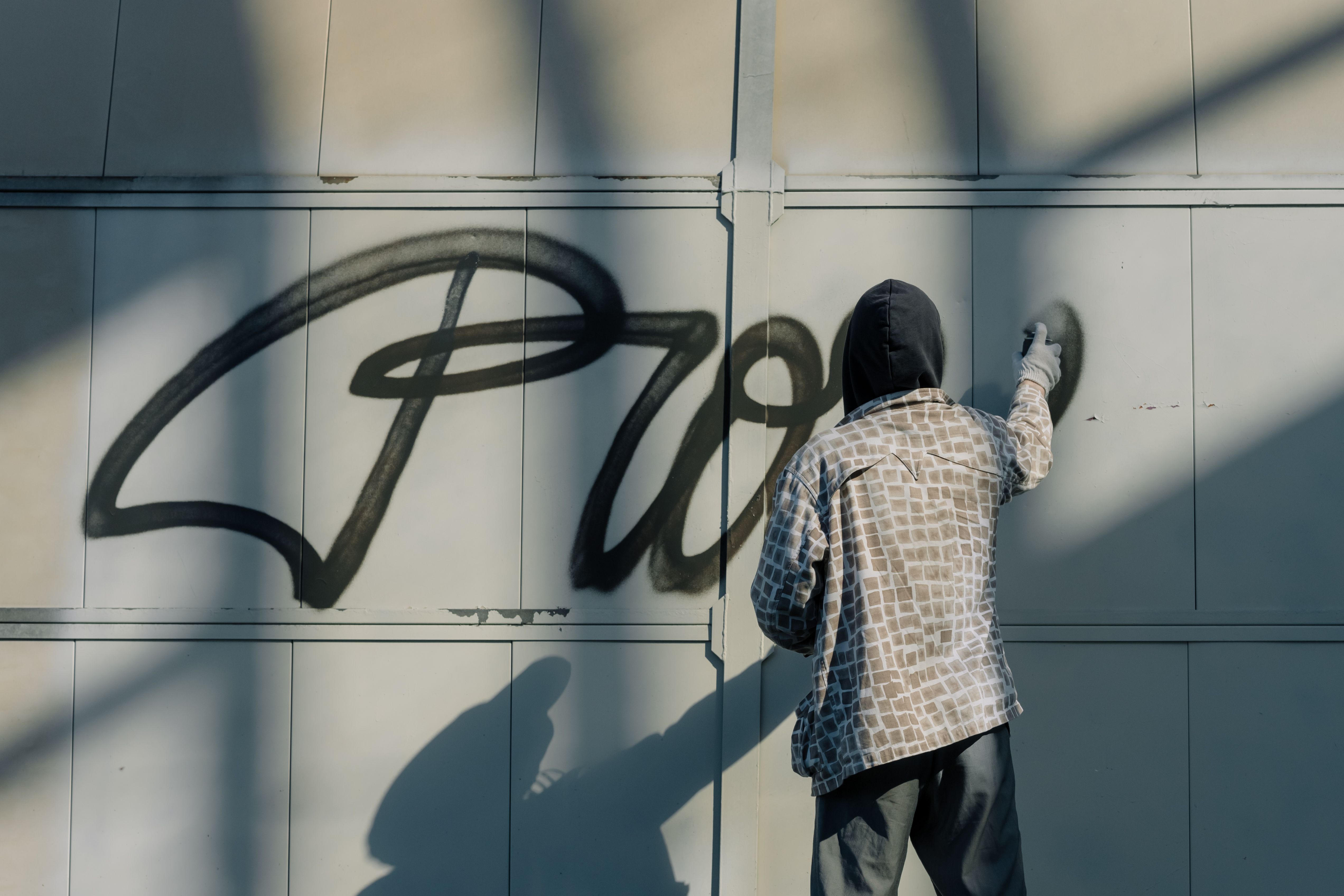 Banksy – fotografische Aufnahme eines vermummten Street-Art-Künstlers beim Sprayen