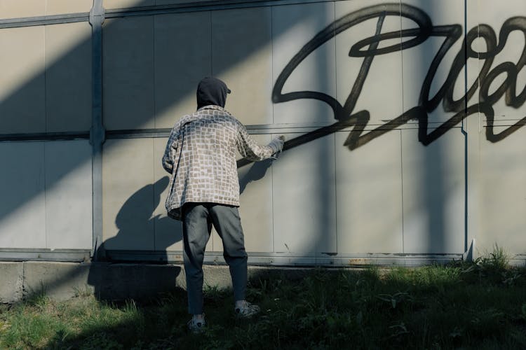 A Person Vandalizing A Wall With Spray Paint