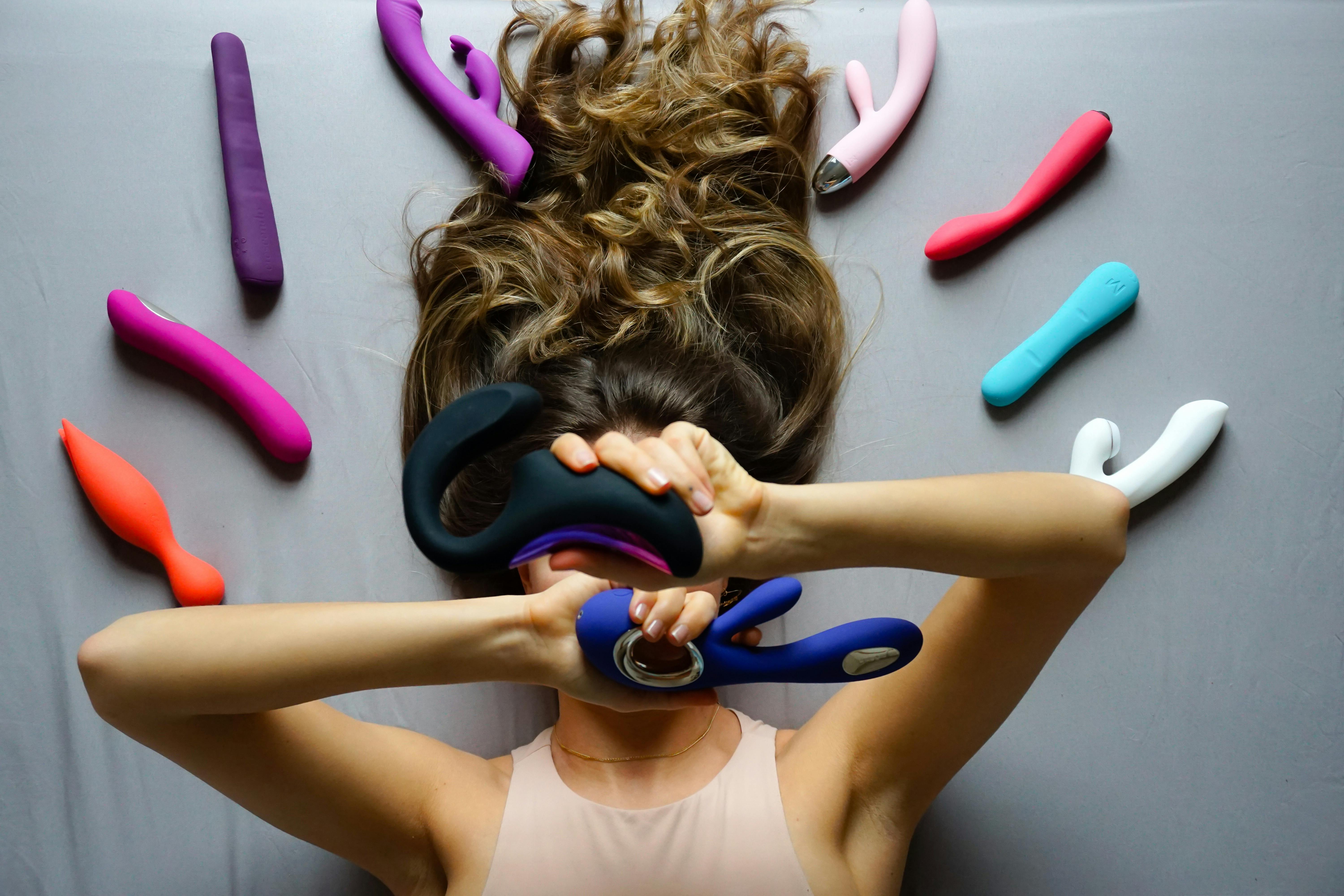 woman lying on the floor and holding a variety of different vibrators