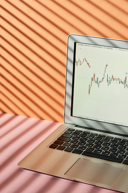Free Laptop displaying stock market graphs with creative light and shadow play. Stock Photo