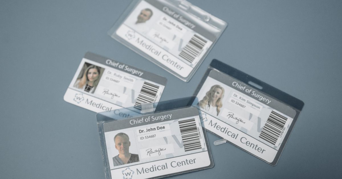Health and Care Worker Visa UK Requirements: Full 2026 Guide — High-angle view of medical ID badges for chief surgeons on a gray surface.