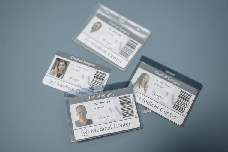 High-angle view of medical ID badges for chief surgeons on a gray surface.