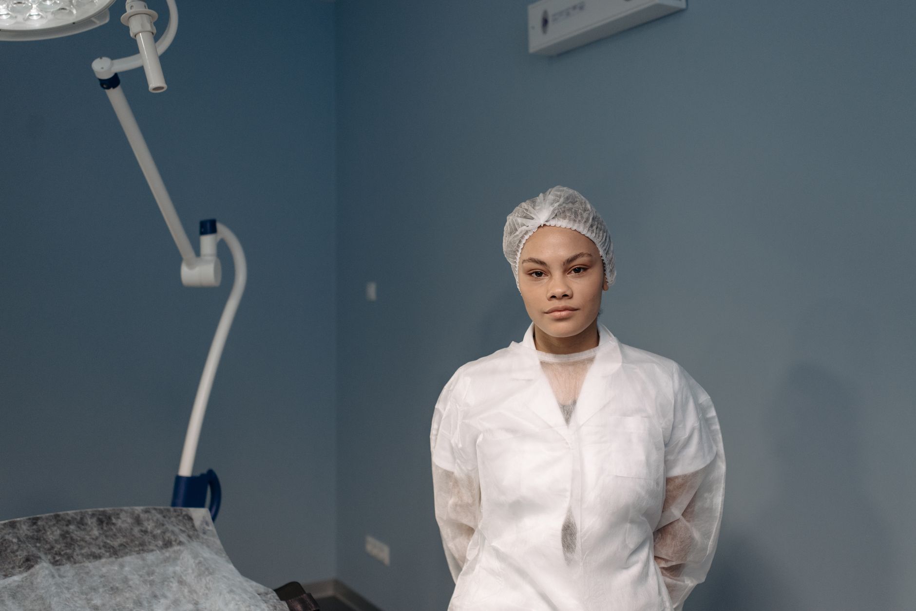 A young female medical professional posing confidently in a clinic room.