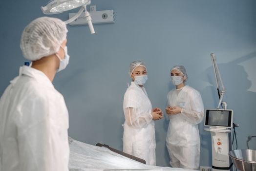 Healthcare professionals in sterile attire conversing in a modern operating room.