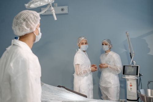 Free Healthcare professionals in sterile attire conversing in a modern operating room. Stock Photo