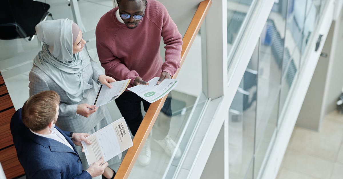 Three diverse colleagues discussing documents in a modern office setting from a high angle view.