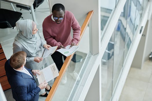 Three diverse colleagues discussing documents in a modern office setting from a high angle view.