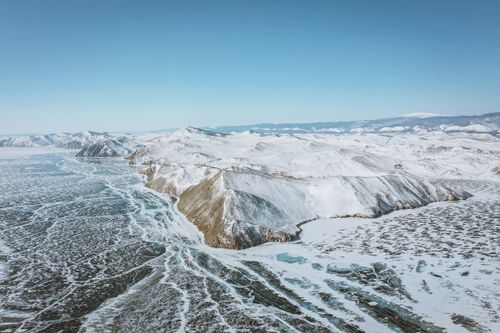 Free Scenic view of mounts with snow on frozen ocean under cloudy blue sky in wintertime Stock Photo