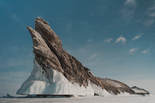 Rock with ice under cloudy sky in wintertime