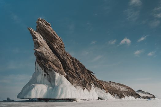 Rock with ice under cloudy sky in wintertime