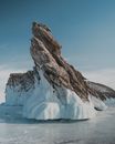 Rock on frozen sea under blue sky in wintertime