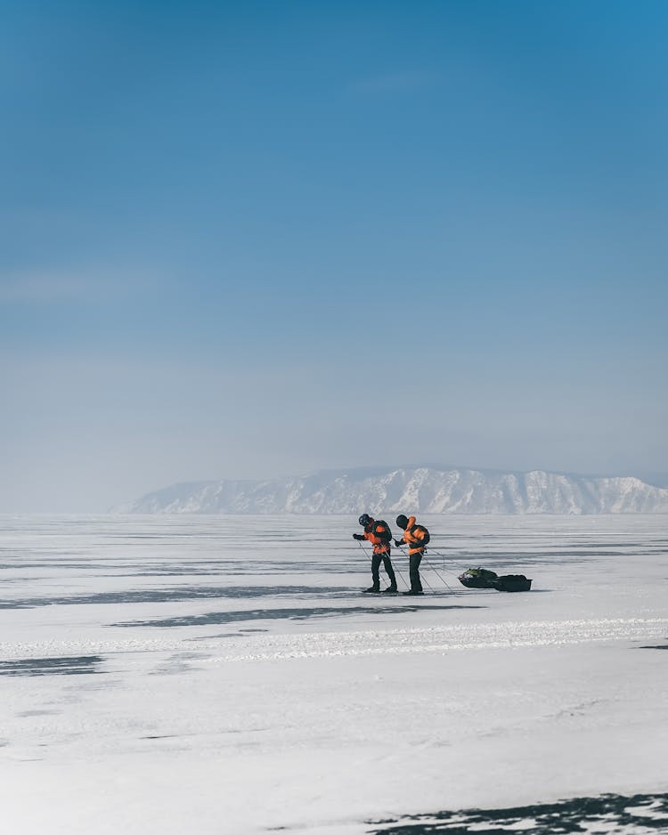 Unrecognizable Backpackers Skiing On Frozen Lake In Winter