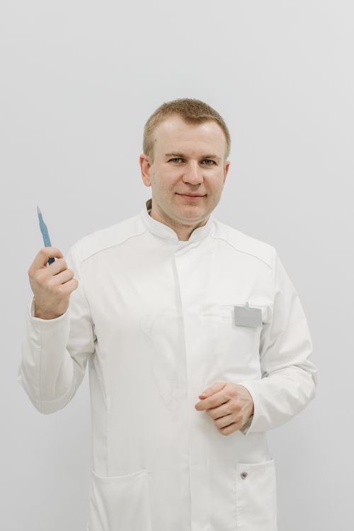 Free A doctor in a white coat holds a medical scalpel against a plain white background, showcasing professionalism. Stock Photo