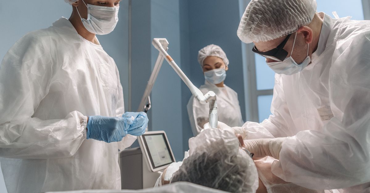 Healthcare professionals in an operating room performing a procedure wearing protective gear.