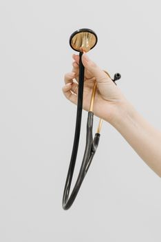 Close-up of a hand holding a stethoscope against a white background, ideal for medical themes.