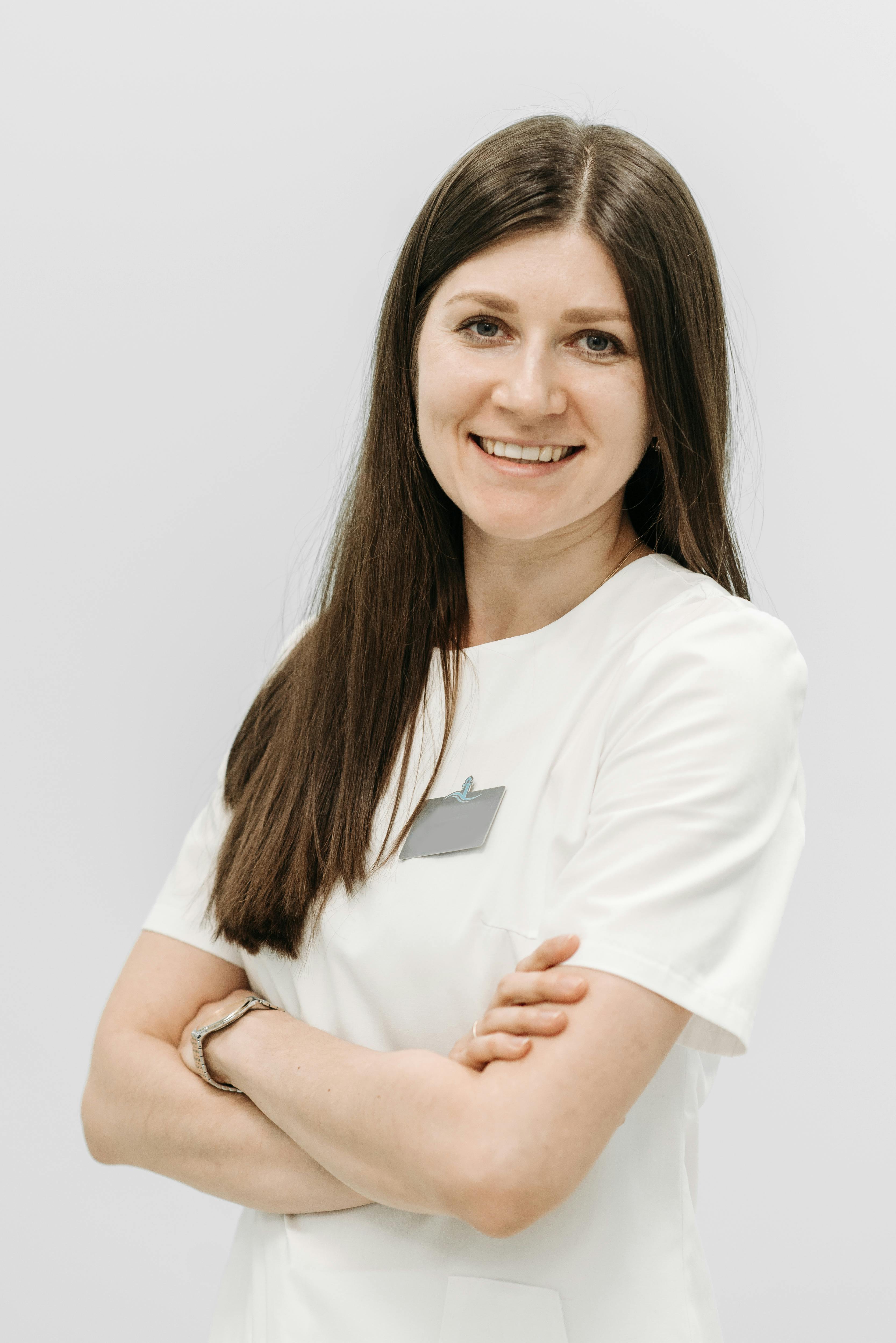 Portrait of a confident woman with arms crossed, smiling in a studio setting.