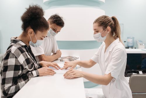 Free A healthcare professional in a medical setting assists patients at a clinic desk, emphasizing care and teamwork. Stock Photo