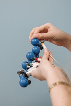 Hands adjusting a blue medical device against a light blue background.