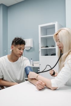 A professional doctor checking a patient's blood pressure in a healthcare clinic.