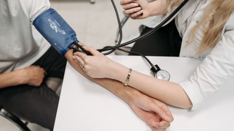 A doctor measures a patient's blood pressure with a sphygmomanometer during a consultation.