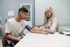 A doctor measures a patient's blood pressure in a clinic setting, focusing on healthcare and wellness.