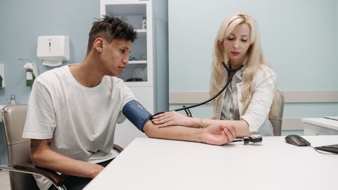 A doctor measures a patient's blood pressure in a clinic setting, focusing on healthcare and wellness.