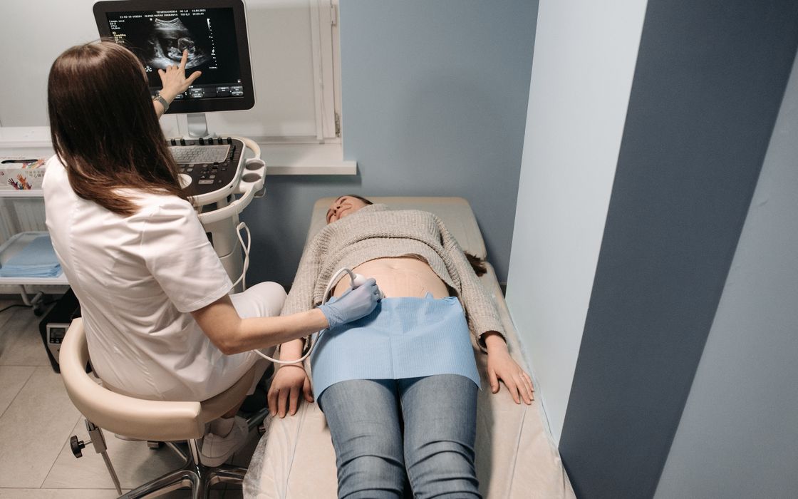 A clinician performs an abdominal ultrasound scan on a patient lying on an examination couch