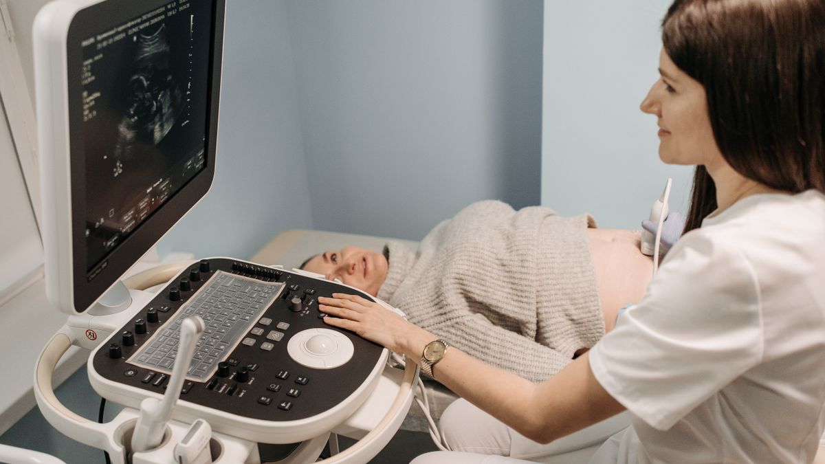 A healthcare professional performing an ultrasound on a pregnant woman in a clinic setting.