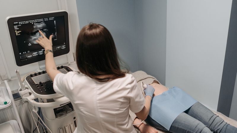 Female doctor conducting an ultrasound screening on a patient in a medical office.
