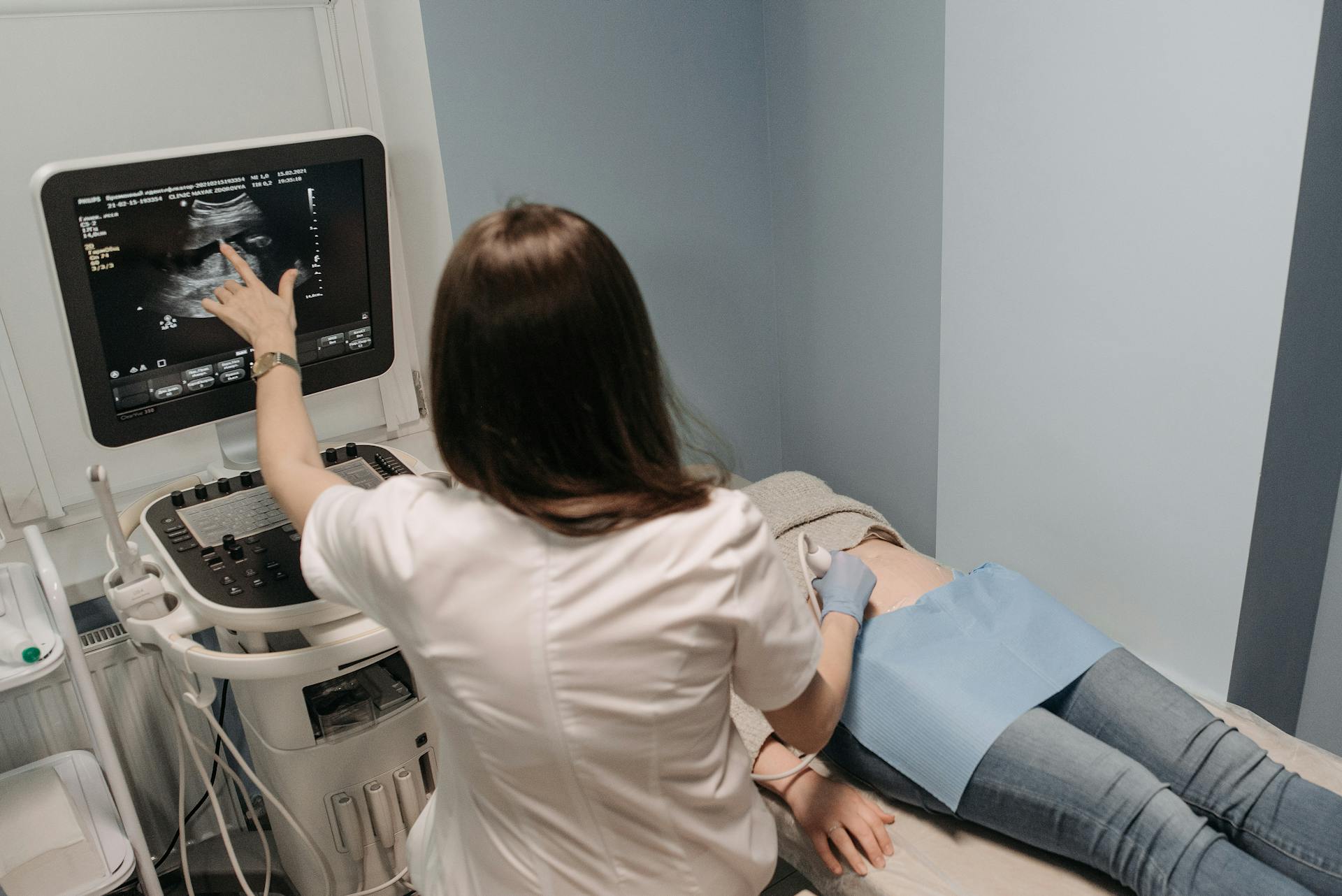 Brunette Doctor Performing Medical Ultrasound and Pointing at Screen