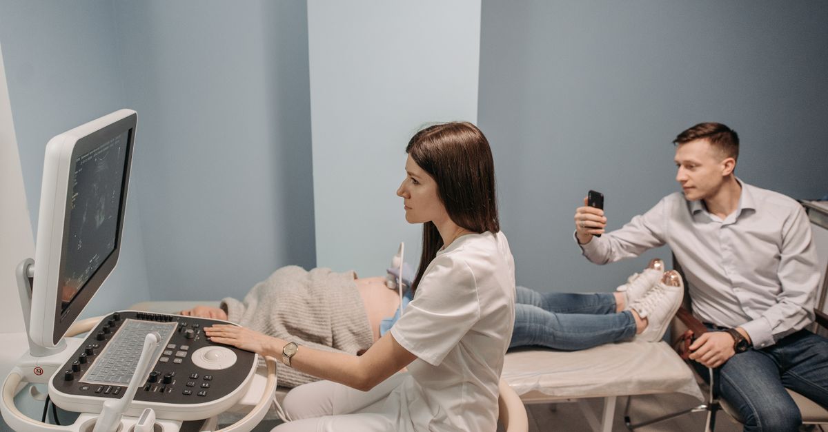 Medical professional conducts ultrasound for expectant couple in clinic.