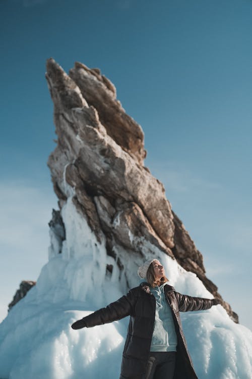 Woman standing near snowy rock