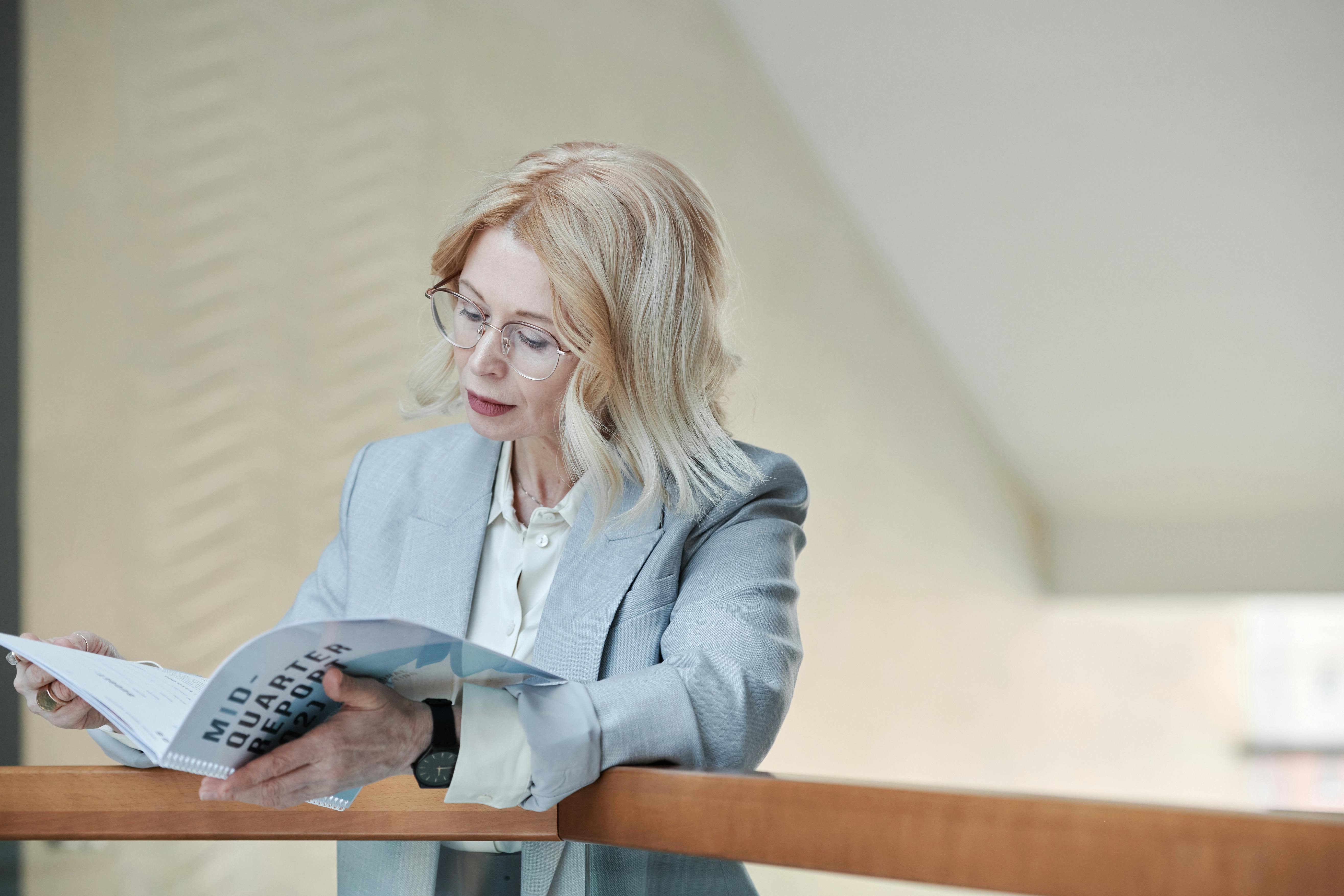 a woman in gray blazer reading a book