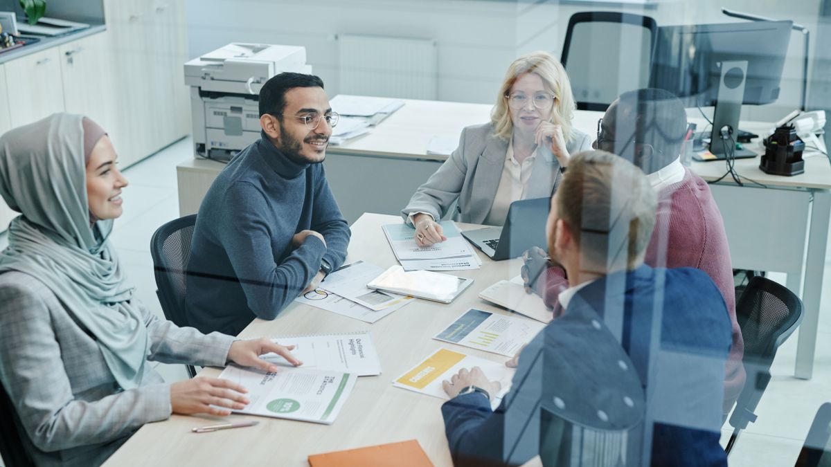 A diverse group of professionals engaged in a meeting at a modern office, promoting teamwork and collaboration.