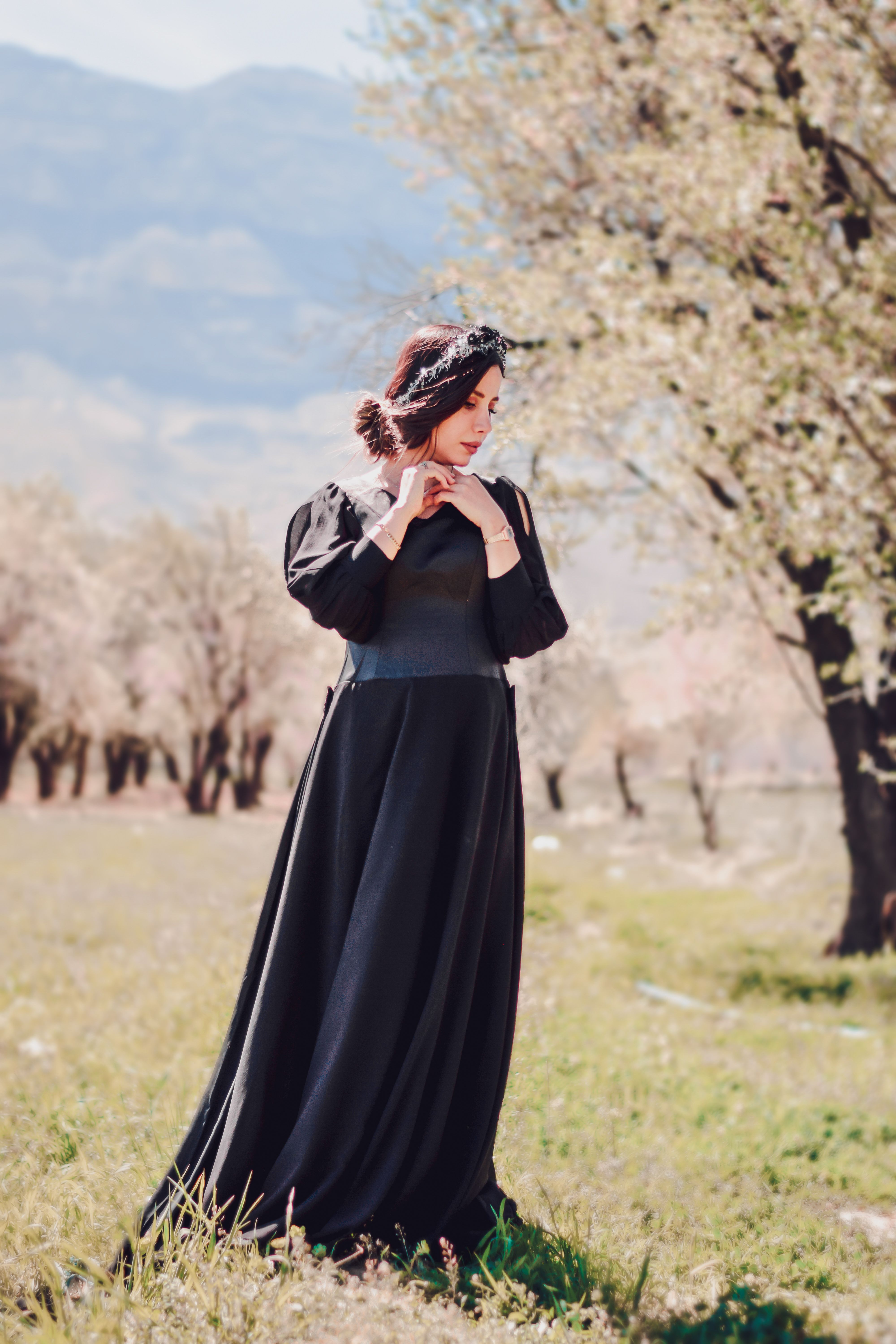 A Woman in Black Dress Standing on a Grassy Field · Free Stock Photo