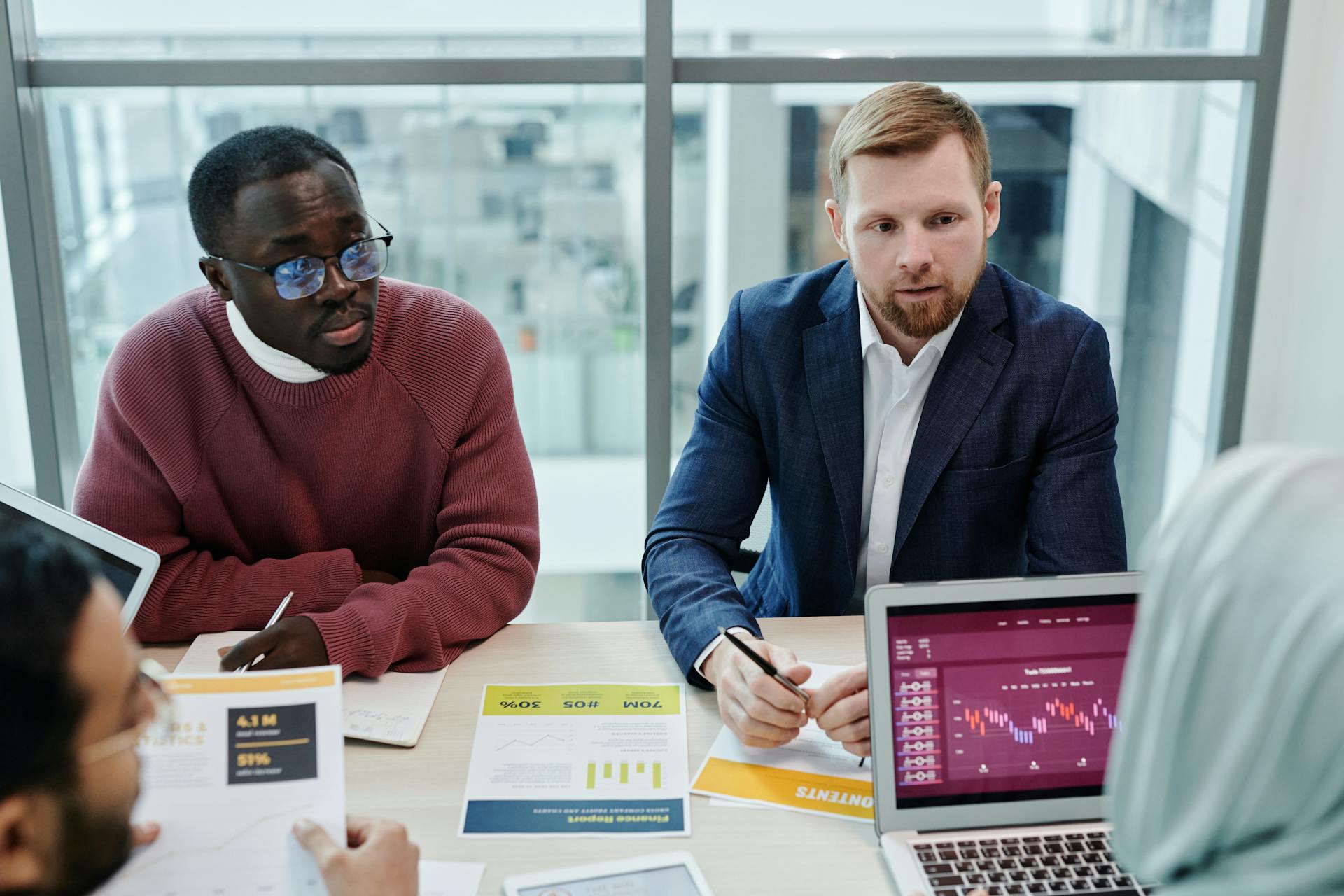 Multicultural team discussing financial data and graphs in a modern office setting.