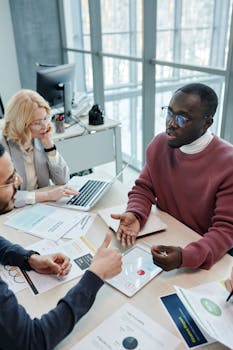 A diverse group of colleagues in a professional office setting engaged in a collaborative meeting.